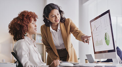 Two business professionals in business attire looking at data on a computer screen